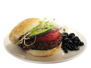 Serving of vegan burger BB and Ohh on a plate with tomato, cucumber, and sprouts. With black beans and a mushrooms on the side. 